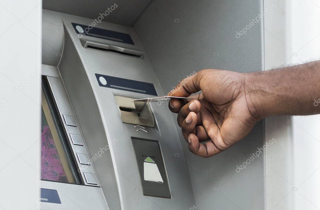 Unrecognizable african man putting credit card into ATM