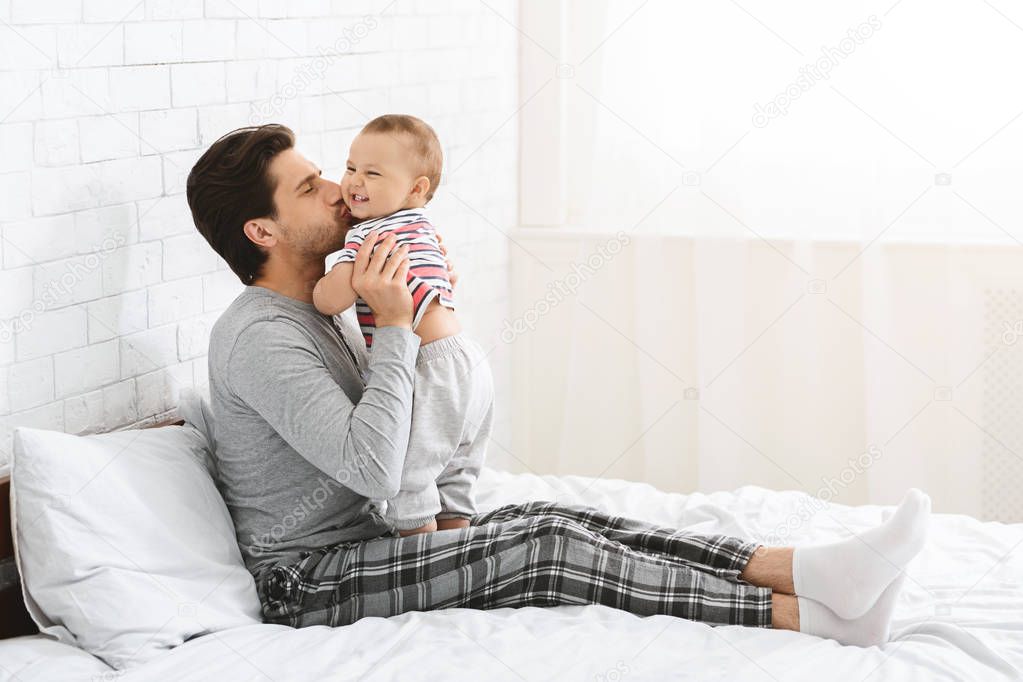 Happy father spending time with baby, kissing son at home