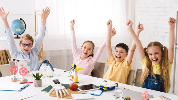Niños felices con las manos levantadas después de la clase de robótica — Foto de Stock