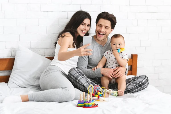 Młodzi rodzice biorąc selfie z ich adorable baby — Zdjęcie stockowe