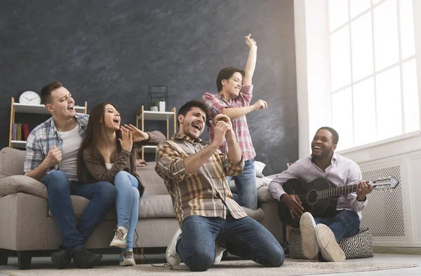 Jovens amigos fazendo festa, tocando guitarra, cantando e dançando em casa — Fotografia de Stock