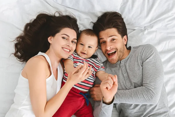 Mère, père et bébé se lient au lit ensemble — Photo