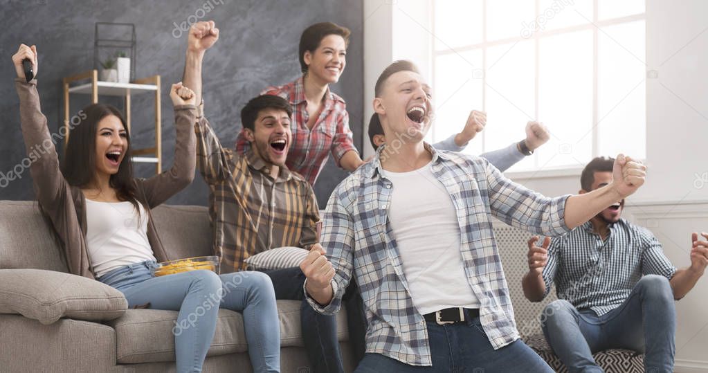 Excited friends having fun by watching football match at home