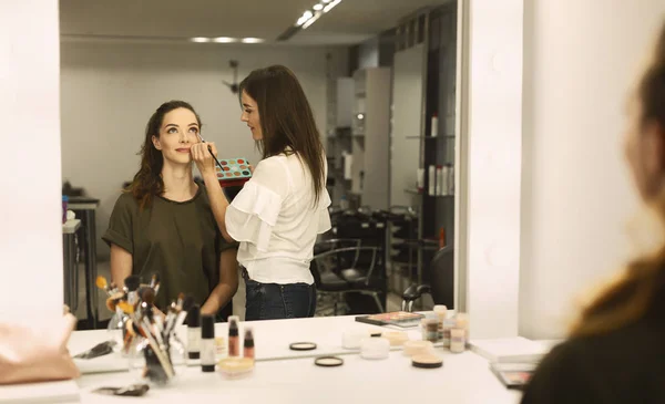 Profesjonalny makijaż artysta stosowanie Eyeshadow do młodej kobiety w salonie — Zdjęcie stockowe