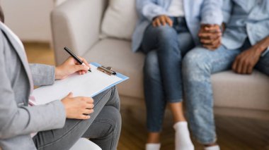 Afro couple holding hands on couch during marriage counseling session clipart