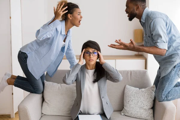 Chokeret ægteskabsrådgiver ser hendes afropatienter Quarrelling In Office - Stock-foto
