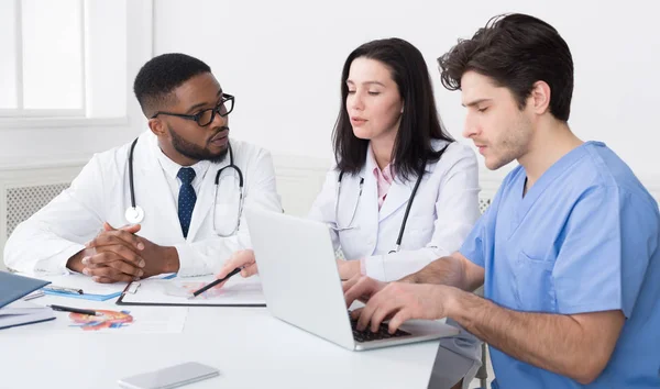 Junges Ärzteteam diskutiert Berichte mit Laptop — Stockfoto