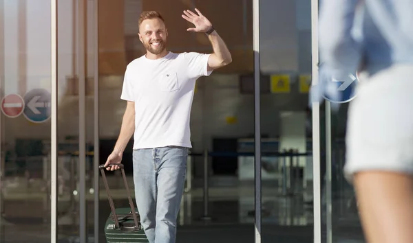 Jovem cumprimentando amigo, chegando ao aeroporto — Fotografia de Stock