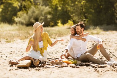 Piknik keyfi genç aile, doğada battaniye üzerinde oturan