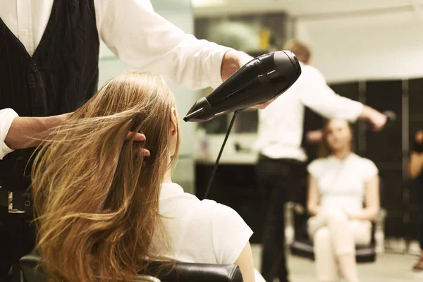 Estilista secado niñas pelo con secador de pelo en salón de belleza —  Fotos de Stock