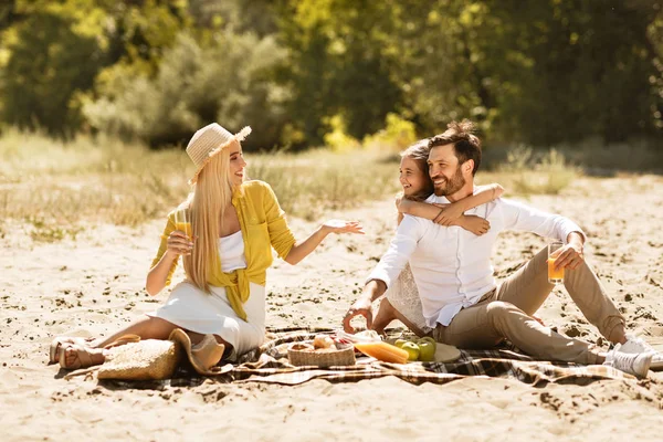 Giovane famiglia godendo pic-nic, seduto su una coperta in natura — Foto Stock