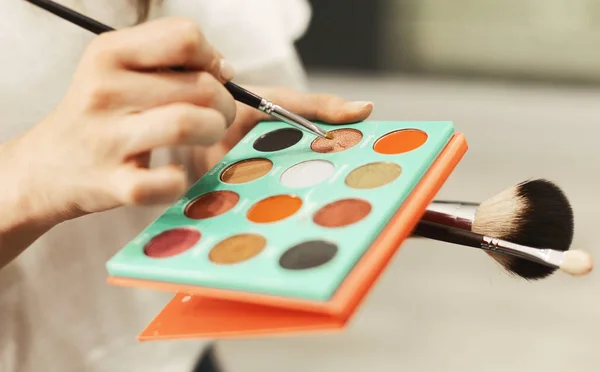 Makeup Artists Hands Holding Brushes And Eyeshadow Palette, Closeup