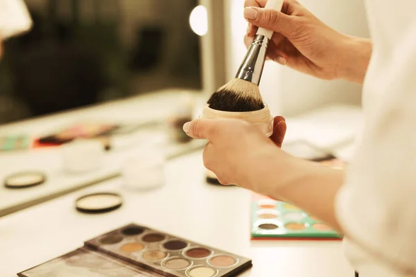 Les jeunes femmes mains tenant la brosse de maquillage et la poudre contre le miroir — Photo