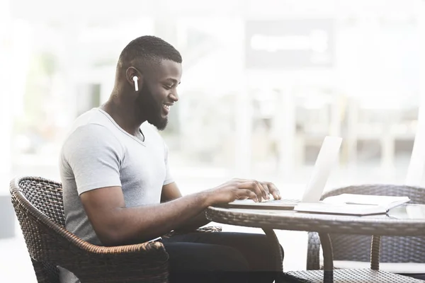 Africký podnikatel psát na notebook a poslouchat hudbu — Stock fotografie