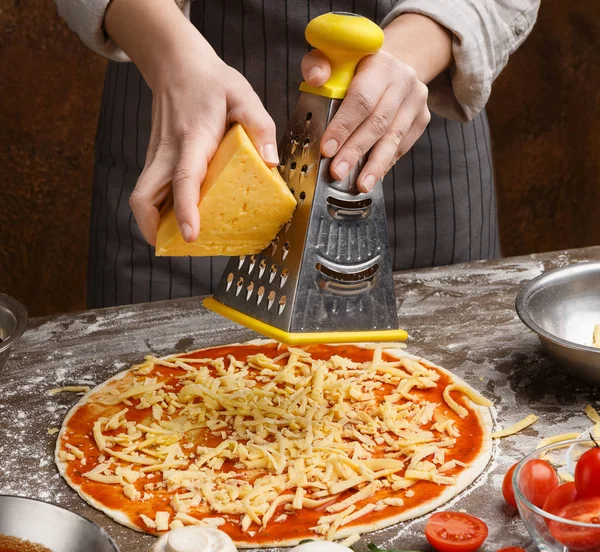 Σεφ τρίβει το τυρί στο τρίφτη στην πιτσαρία κουζίνα — Φωτογραφία Αρχείου
