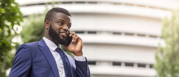Bearded African American businessman talking on cell phone with customer