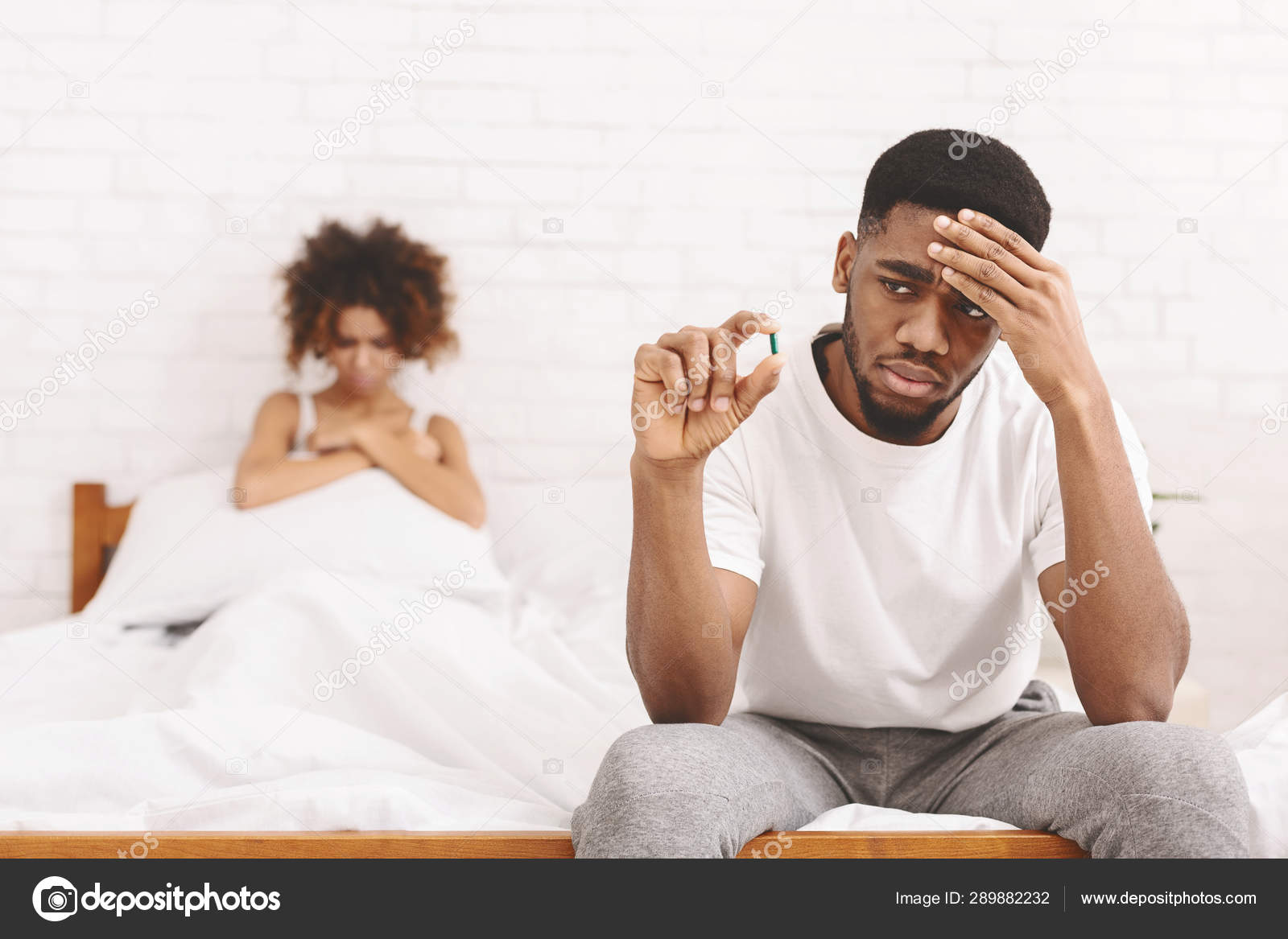 Upset black guy taking potency pill before sex with girlfriend Stock Photo by ©Milkos 289882232