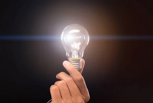 Bulb with light inside in man hand on black background — Stock Photo, Image