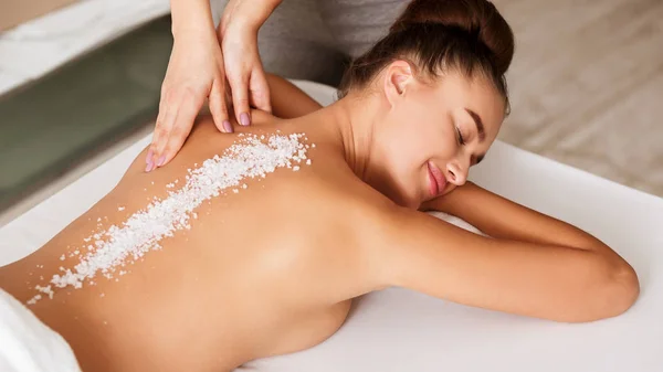 Relaxed woman enjoying salt scrub massage at spa — Stock Photo, Image