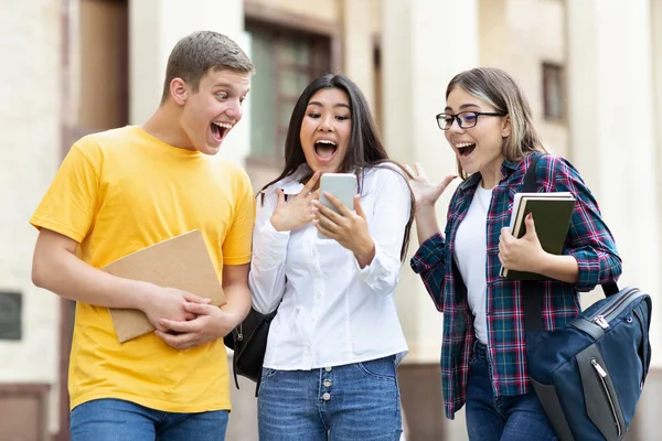 Здивовані студенти перевіряють результати іспиту на смартфоні — стокове фото