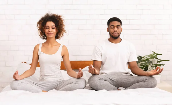Fiatal fekete család, együtt meditáció az ágyban — Stock Fotó