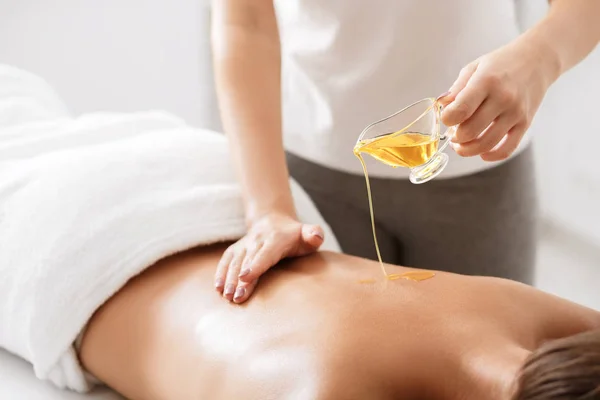 Masseur pouring aroma oil on female back — Stock Photo, Image