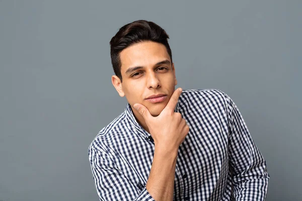 Pensive Hispanic Man Touching His Chin On Gray Background