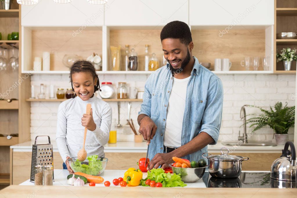 Father and daughter preparing fresh salad in kitchen