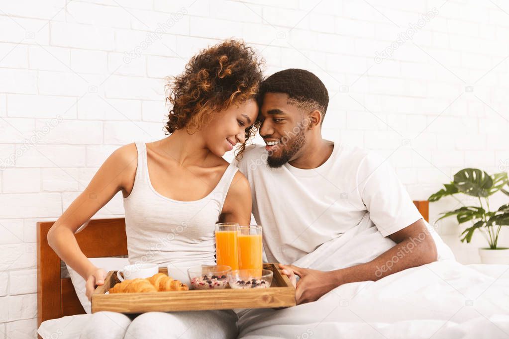 Happy black couple enjoying breakfast in bed