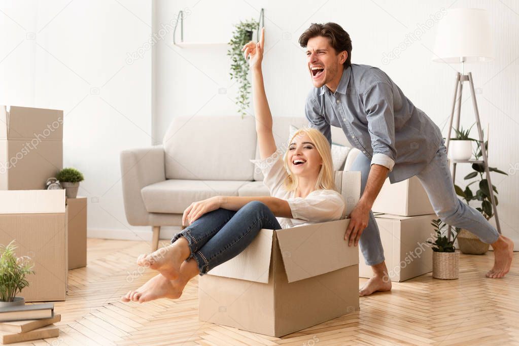 Joyful Couple Packing Boxes For A Move And Having Fun