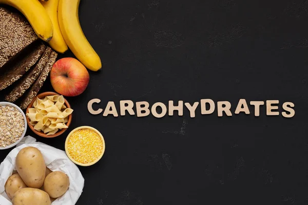 Texto de carboidratos com alimentos saudáveis em fundo preto — Fotografia de Stock