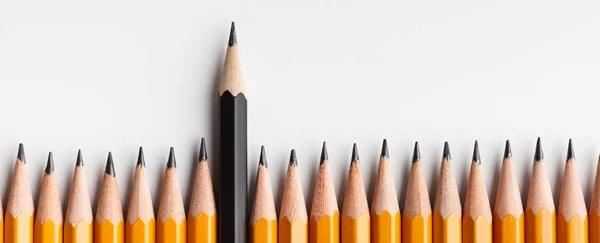 One black pencil protruding out of line with similar ones