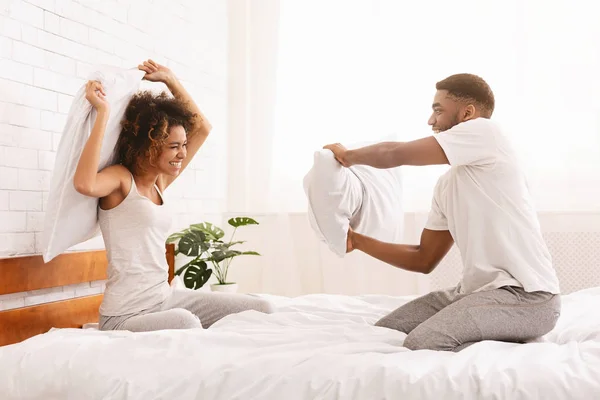 陽気な愛情のあるカップルはベッドの枕で戦ってください。. — ストック写真