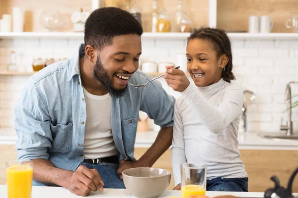 Adorable afro chica alimentando a su papá cereales —  Fotos de Stock