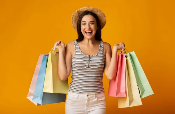 Mooi meisje poseren met kleurrijke boodschappentassen over gele achtergrond — Stockfoto