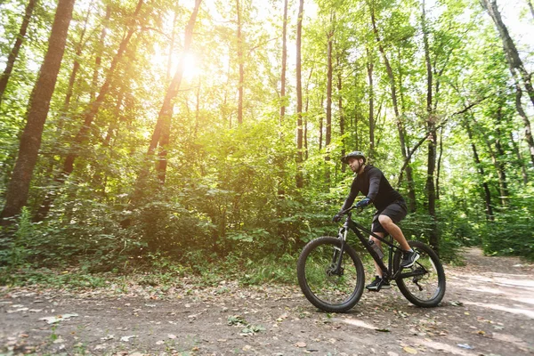 Ciclista masculino montando em trilhas florestais em chamas de sol — Fotografia de Stock