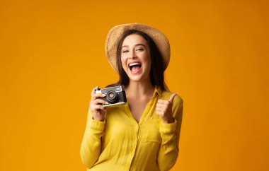 Retro Kamera Gesturing Thumb Up ile Toursit Girl. Sarı Arka Plan