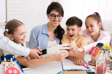 Sınıfta çocuklara robotik el gösteren öğretmen