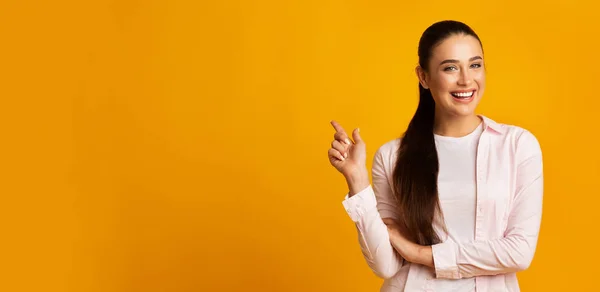 Bella donna puntando dito a spazio vuoto su sfondo giallo — Foto Stock