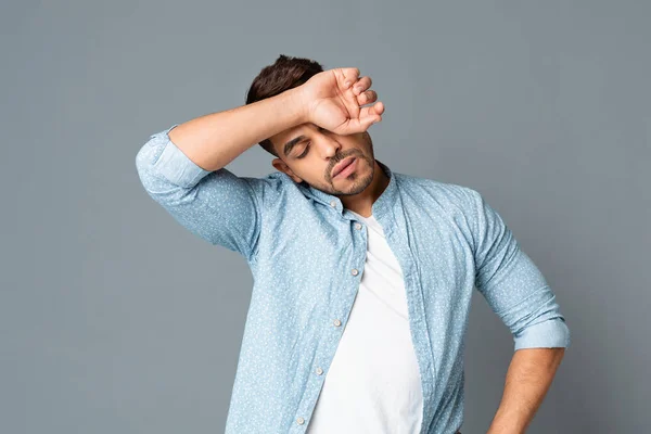 Erschöpfter hispanischer Mann wischt sich Schweiß von der Stirn auf grauem Hintergrund — Stockfoto