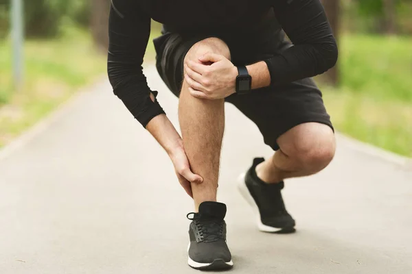 Мужчина бегун страдает от боли в лодыжке на пробежке — стоковое фото