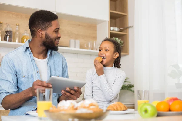 Pappa och dotter äter kakor och kollar på nytt recept — Stockfoto