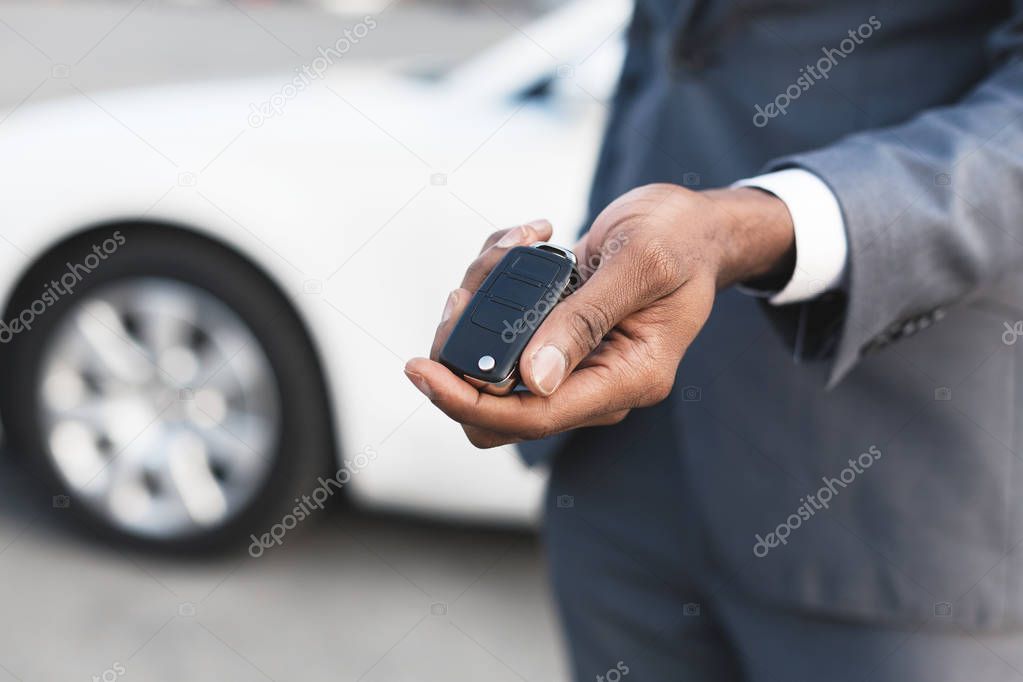 Car rental concept. Young man showing key of his new car