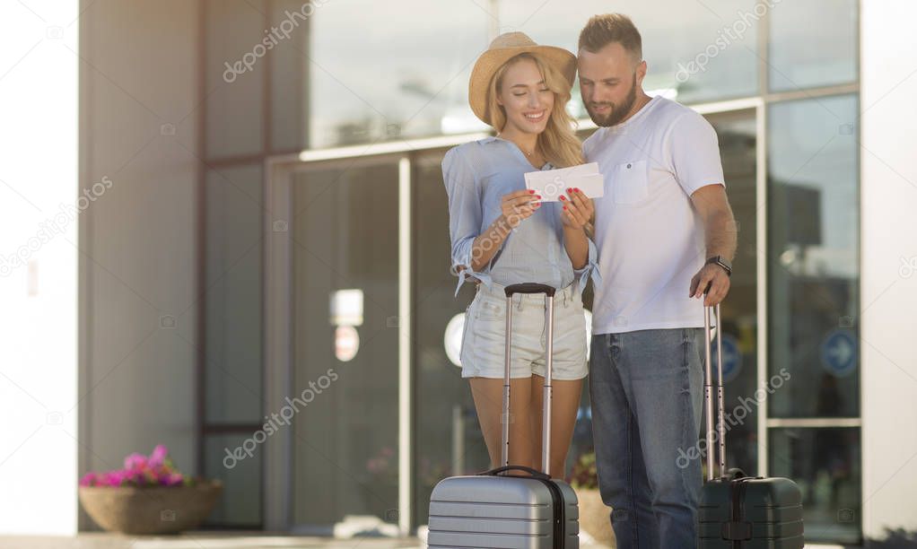 Millennial couple checking tickets in front of airport entrance