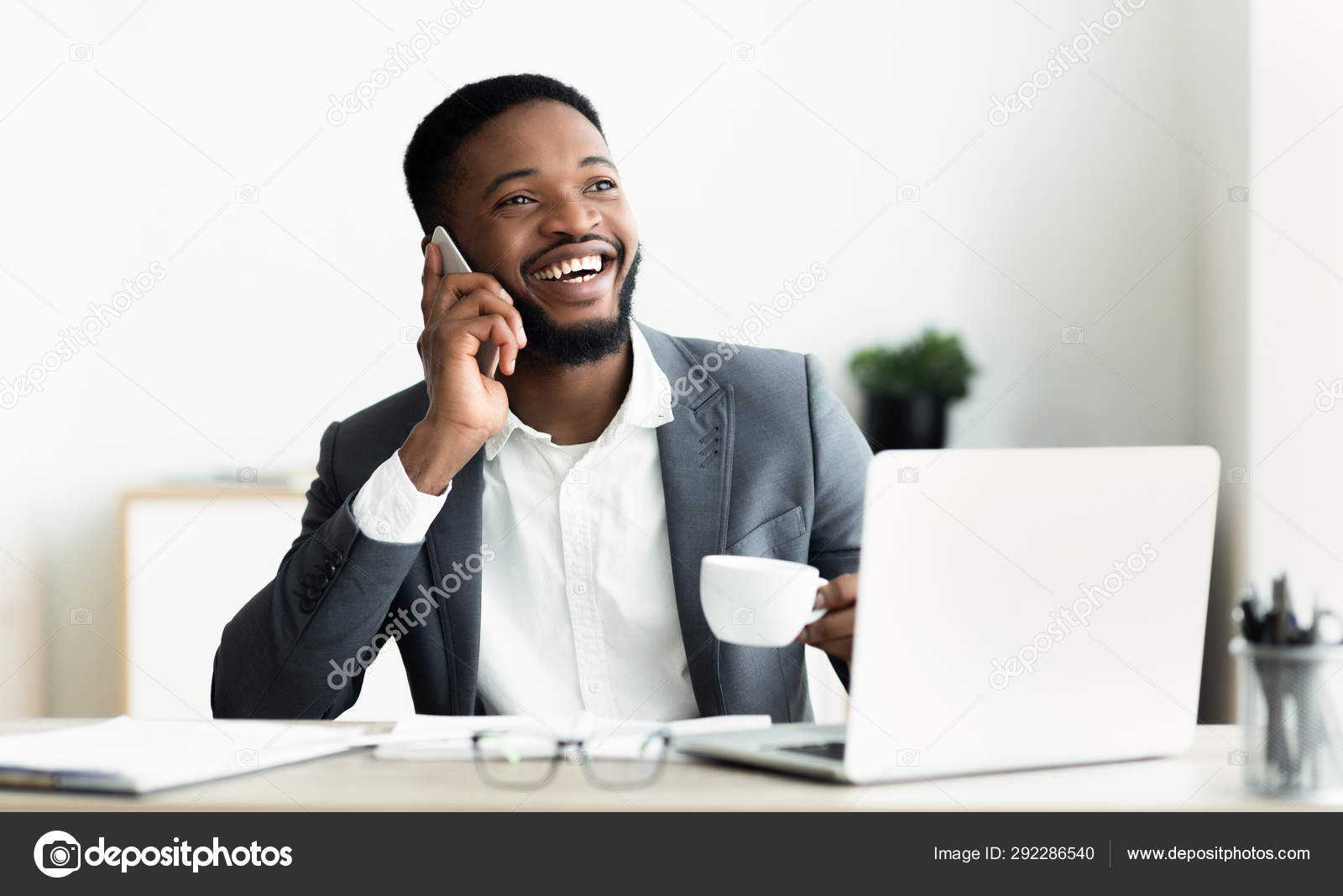 Homme d'affaires noir parlant sur téléphone mobile et travaillant sur  ordinateur portable — Photo de stock par ©Milkos - 292286540, image size:1600x1068