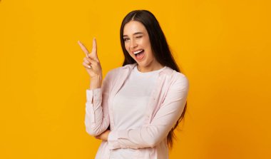 V-Sign Gösteren Kadın Ve Sarı Arka Planda Kameraya Göz Kırpma