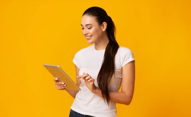Lovely Girl Sarı Stüdyo arka plan üzerinde dijital tablet kullanma