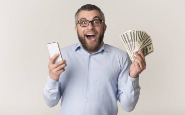 Mutlu adam akıllı telefon tutan ve para demet gösteren