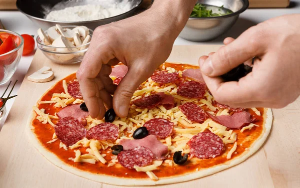 Pizzaiolo macht Pizza, fügt schwarze Oliven hinzu und dekoriert sie — Stockfoto