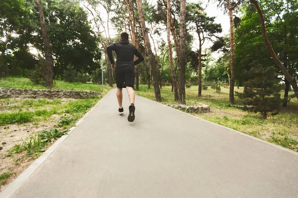 Joven deportista corriendo en el parque arbolado — Foto de Stock